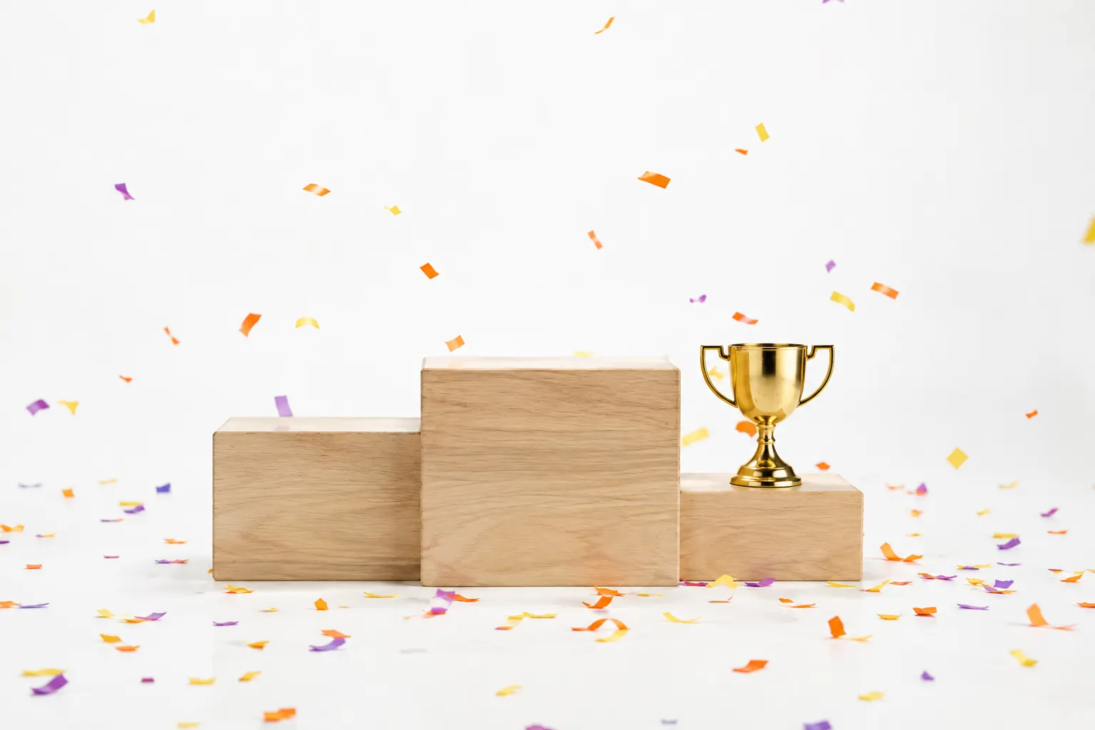Podium à trois marches avec une coupe en laiton et des confettis, pour illustrer comment marche un concours SEO