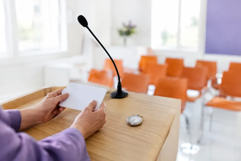 Mains tenant des fiches vierges près d’un pupitre et d’un micro pendant une répétition